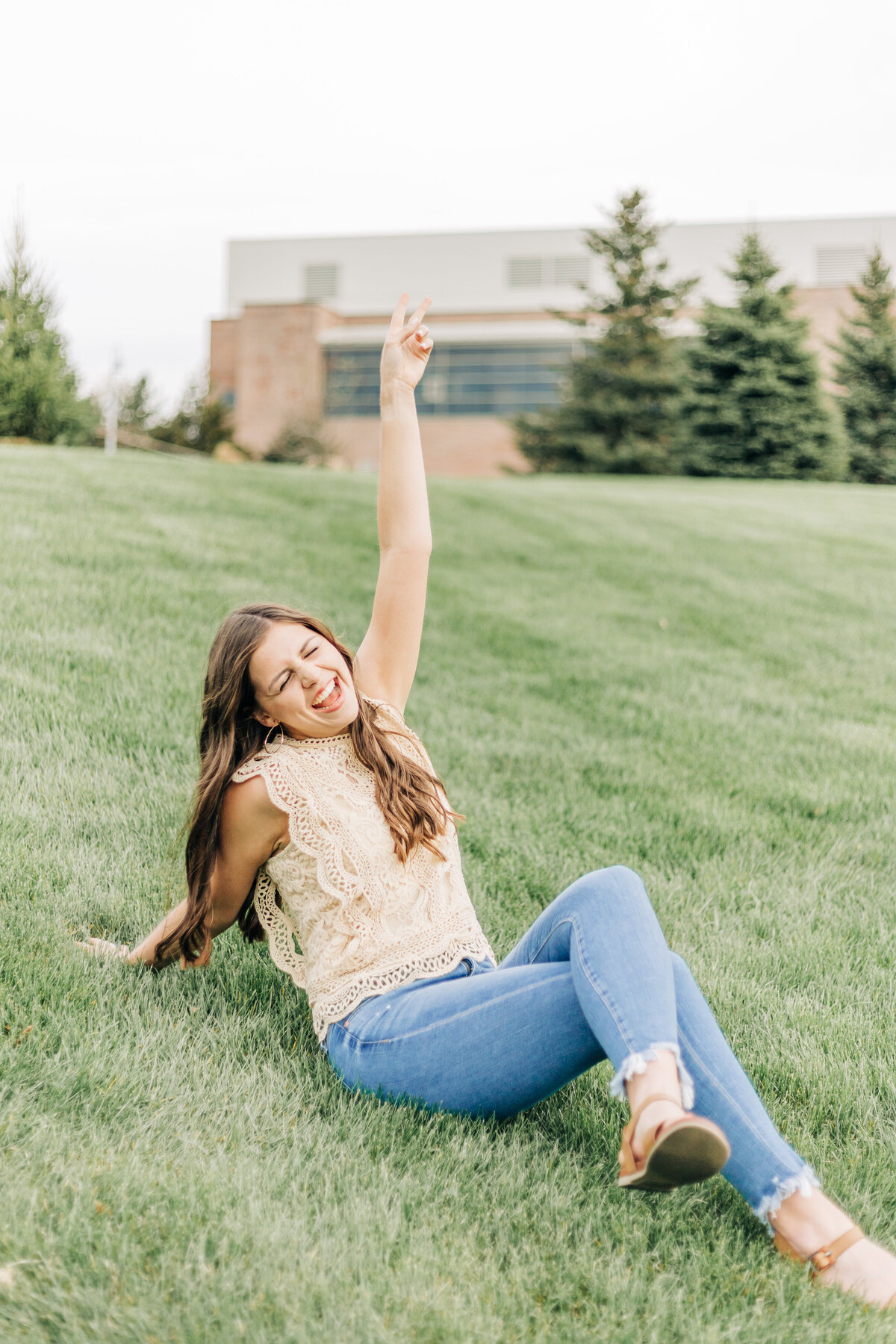 girl sitting in the grass doing peace and getting excited