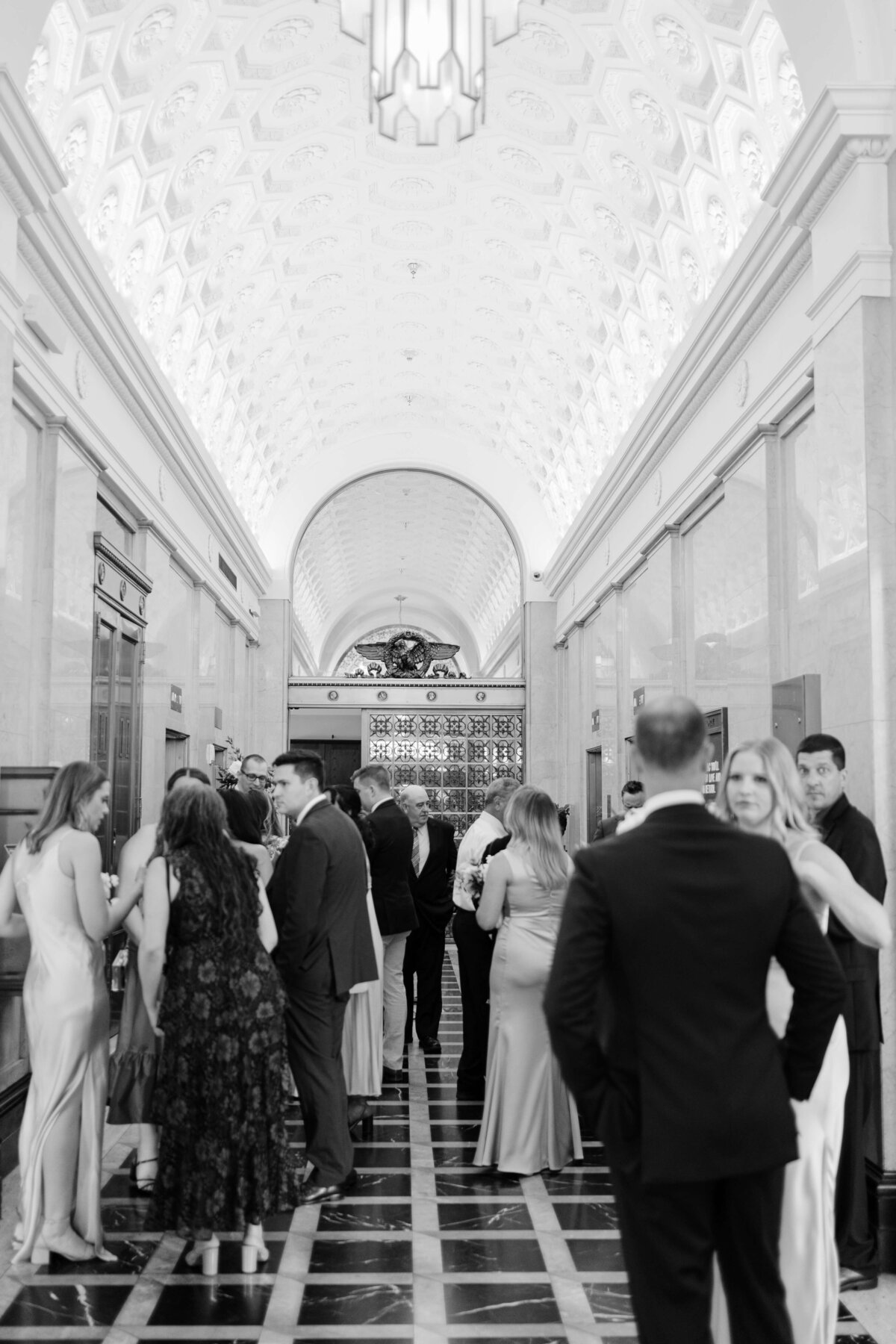 A wedding party mingle in the vault of the Riggs Hotel DC.