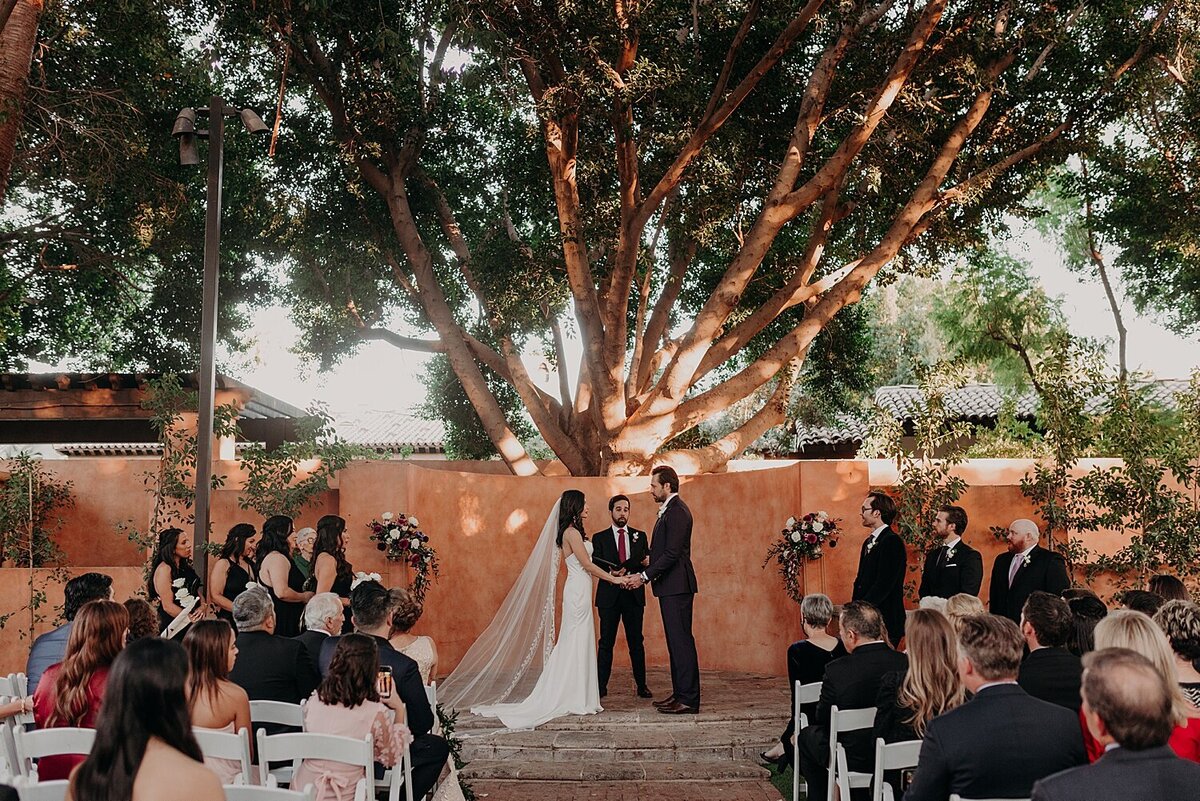 wedding ceremony under large tree at spanish inspired venue
