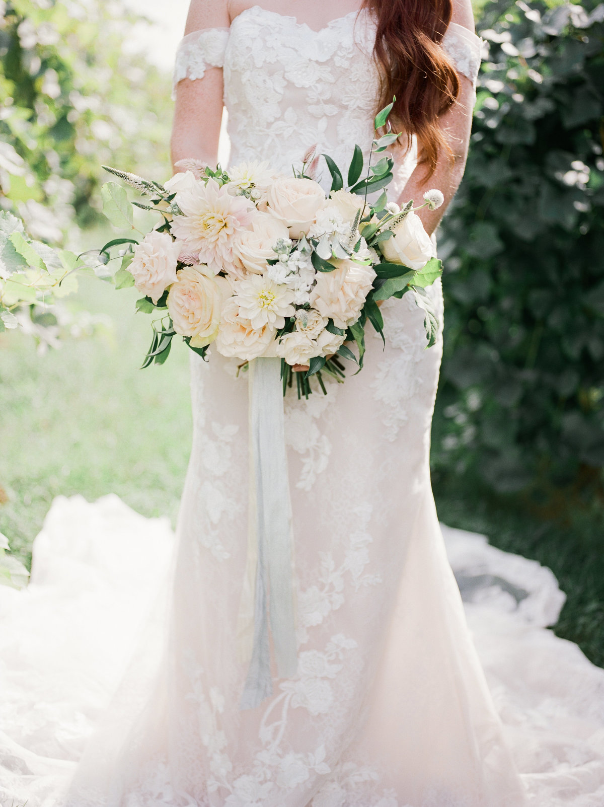 bride wearing strapless lace wedding gown holding white rose bouquet