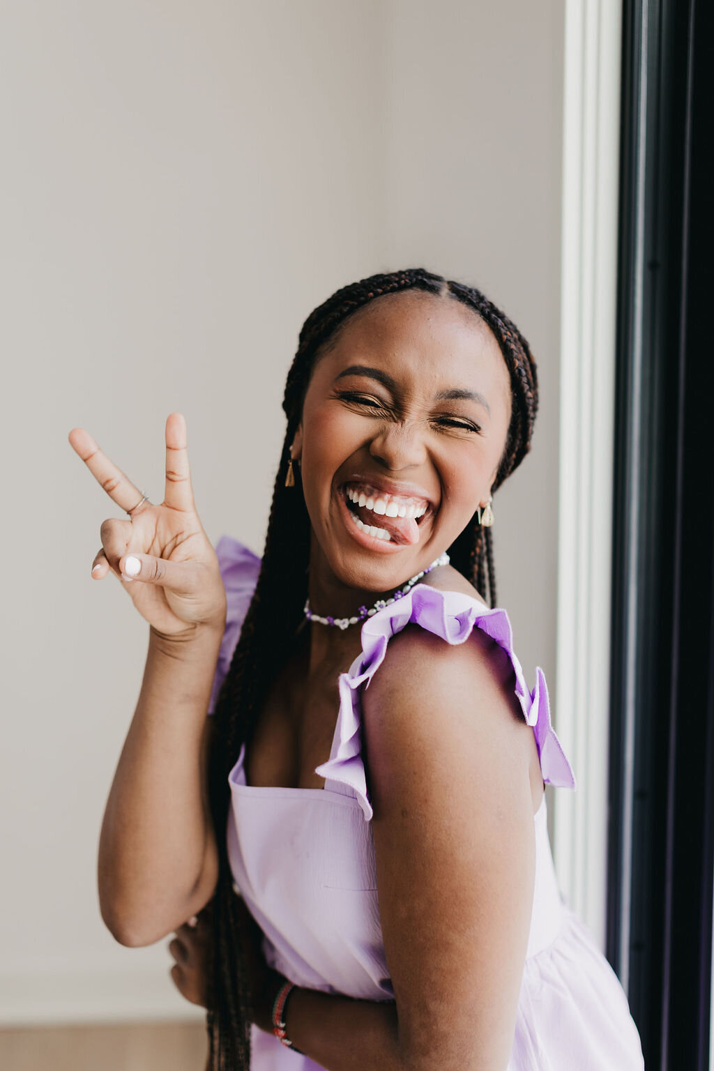Juma Waganda in a purple top smiling and holding up a peace sign