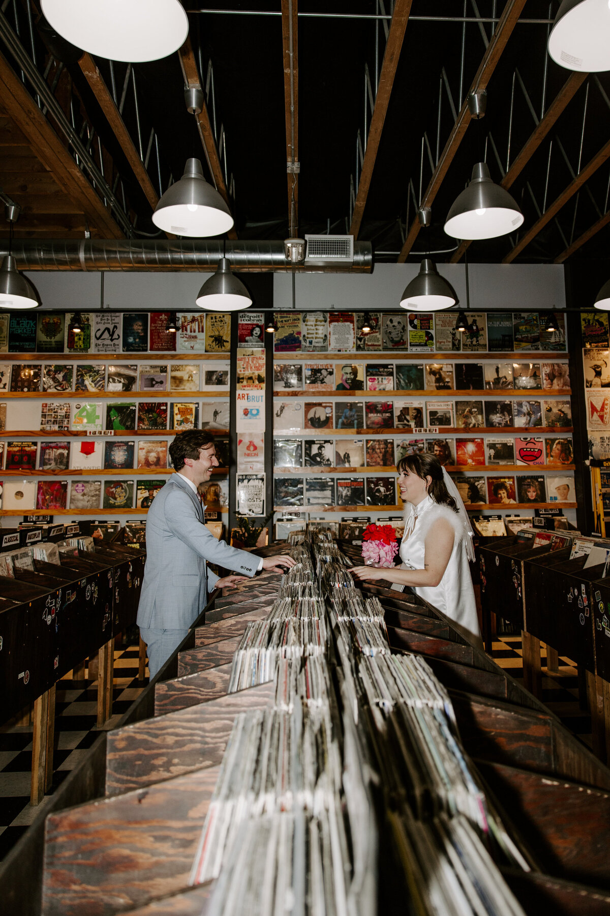Two people search through vinyls at a record shop.