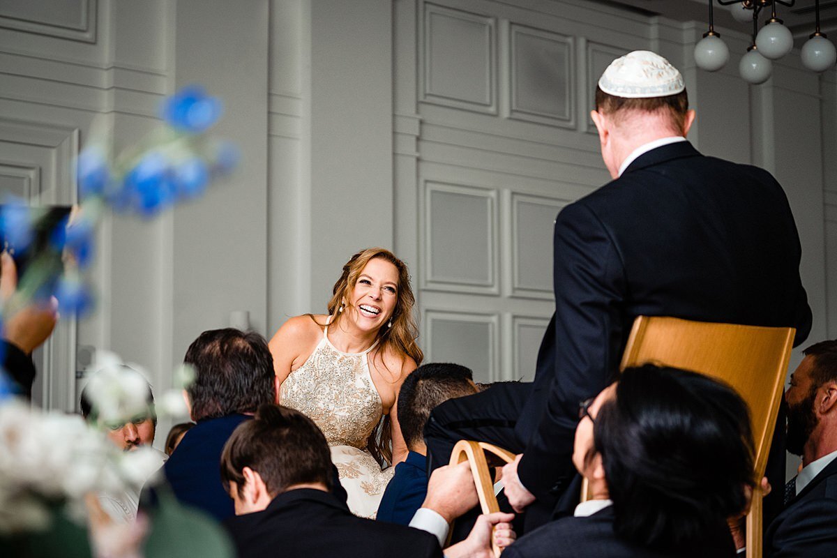 Dancing the hora at a Jewish wedding in Nashville as the bride and groom are raised up on wooden chairs above the guests.