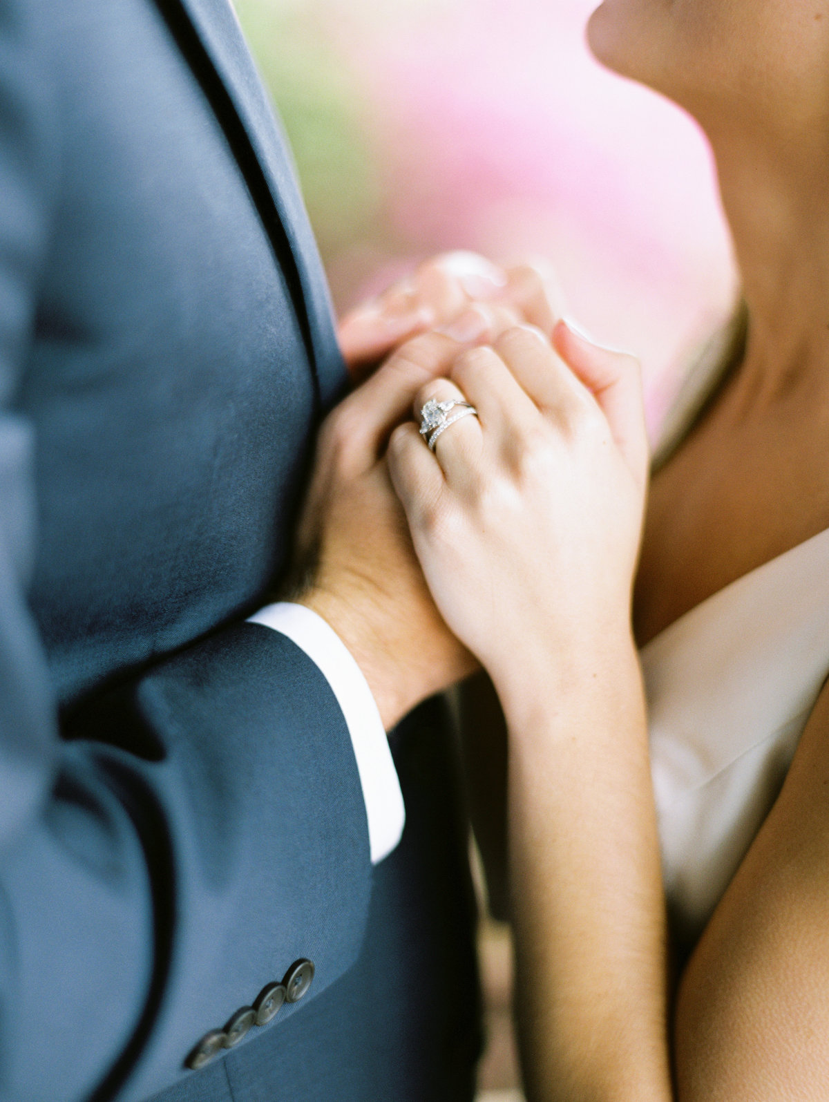 Bride and groom holding hands with wedding ring showing.