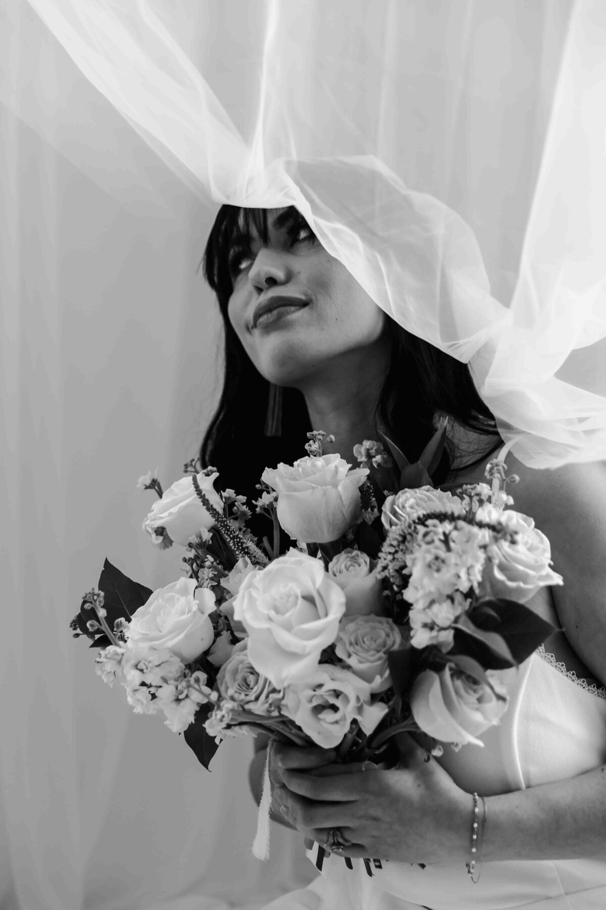 bride with bouquet under veil in black and white