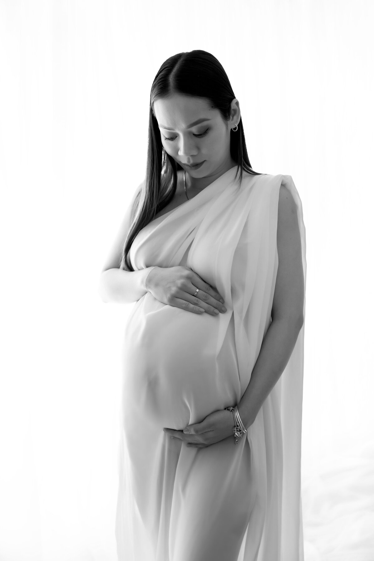 Chicago maternity photographer captures a beautiful moment of mom looking down at her bump with her hands around her belly. 