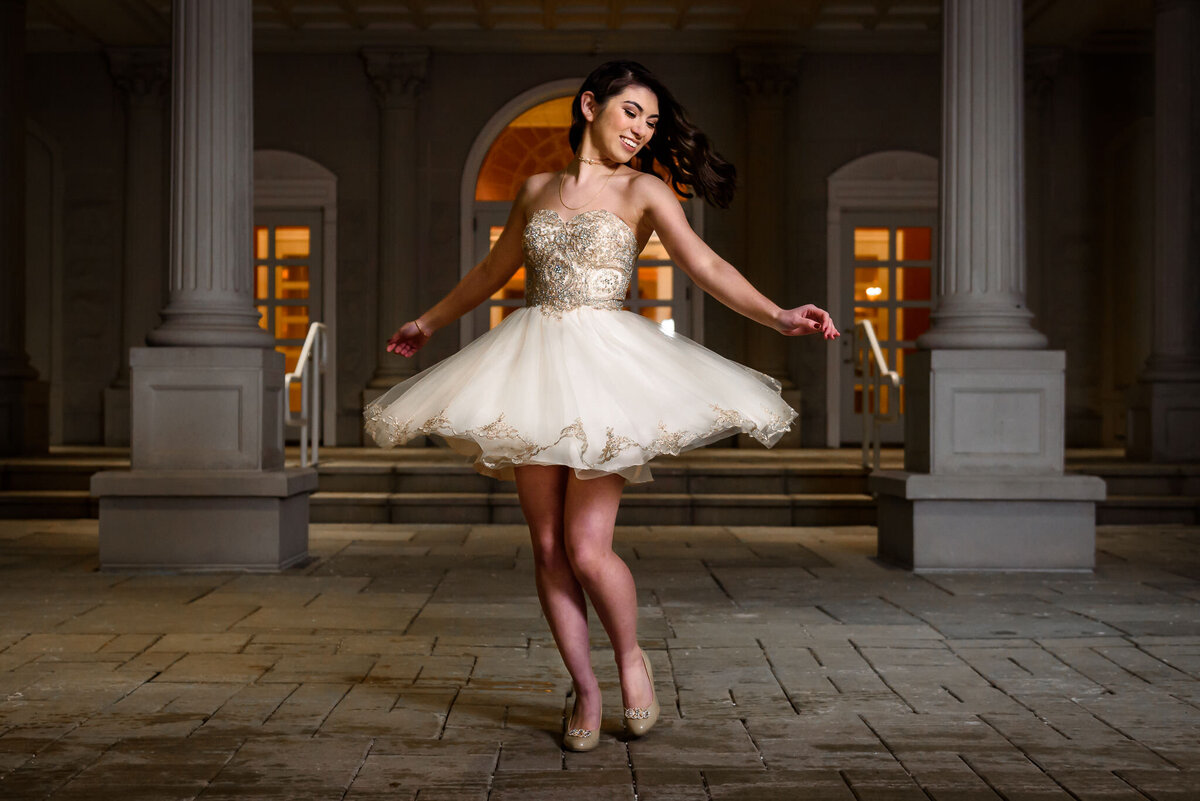 A young woman in a dress dances outside of a building