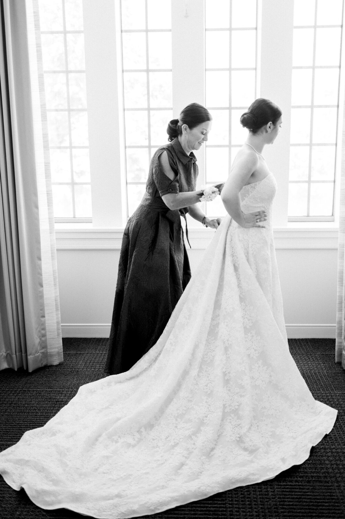 a woman helping a bride with her dress