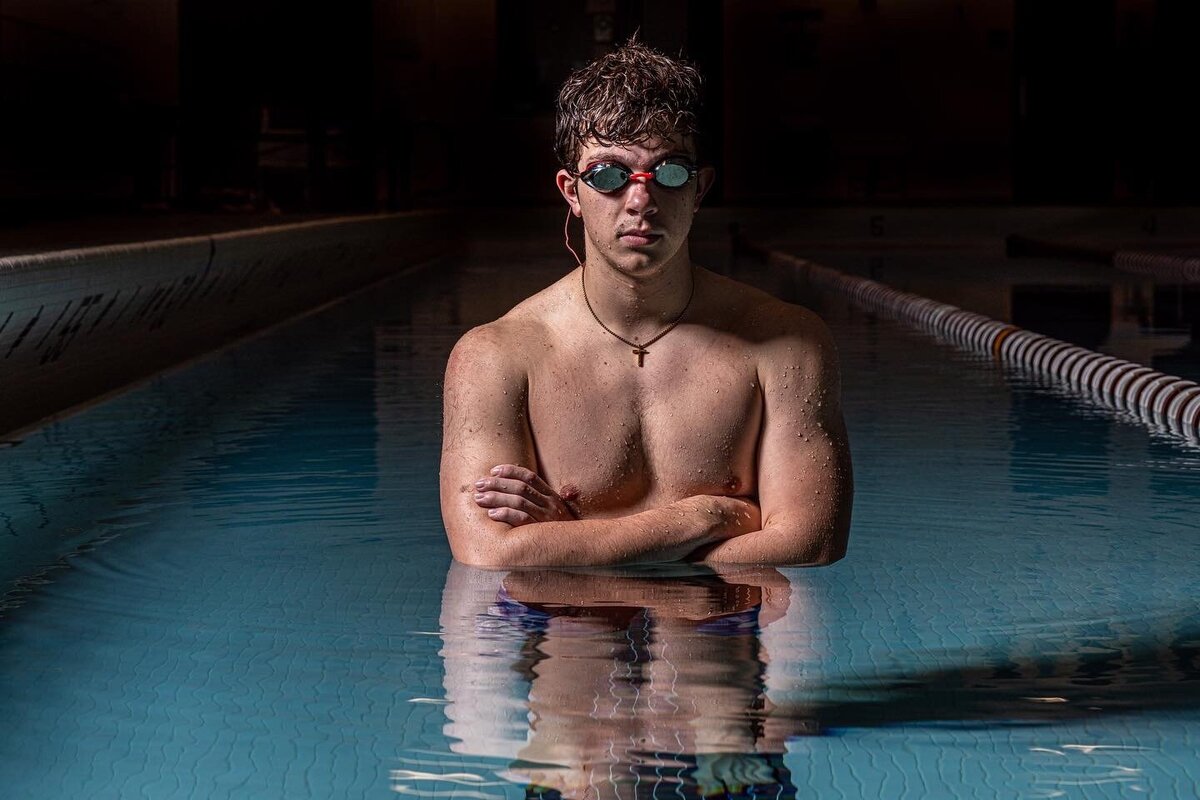 CT Photographer | Rob Faber Photography | Swim Photos- simmer standing in pool with arms crossed and dark background.