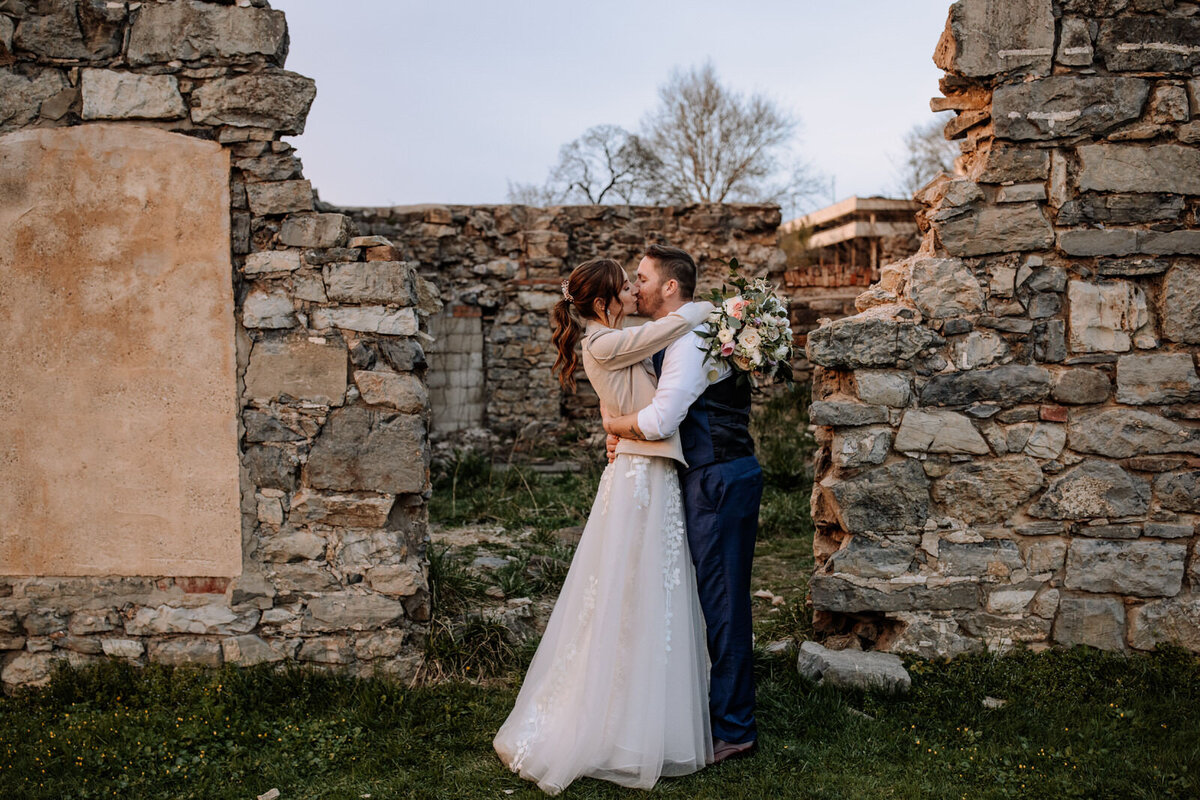 Bride and groom holding hands looking at each other while standing in front of rolling hills with the sunlight coming down on them