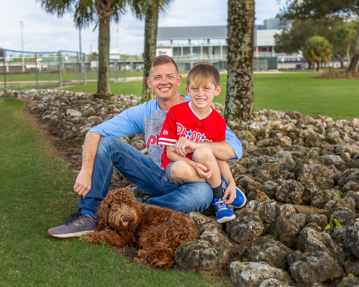 father and son sitting by rocks smiling