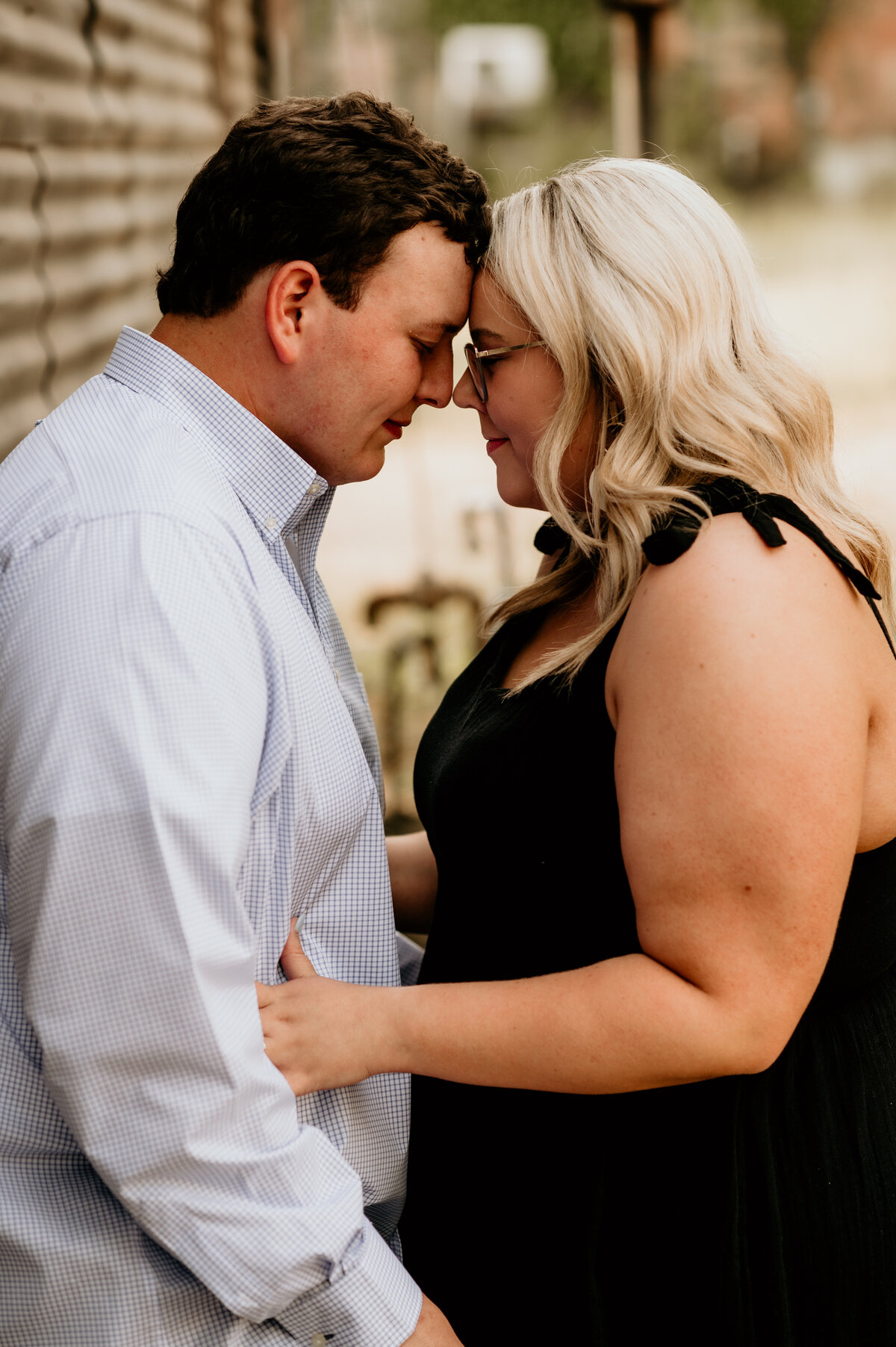 man and woman embraces each other as they rest their foreheads together and gently smile photographed by little rock engagement photographers