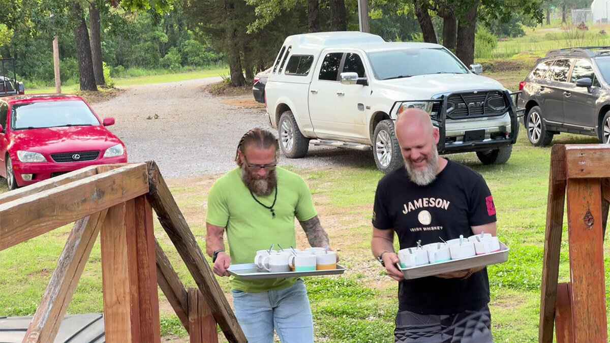 A photo of two veteran brothers bringing inside cacao for a group cacao ceremony.