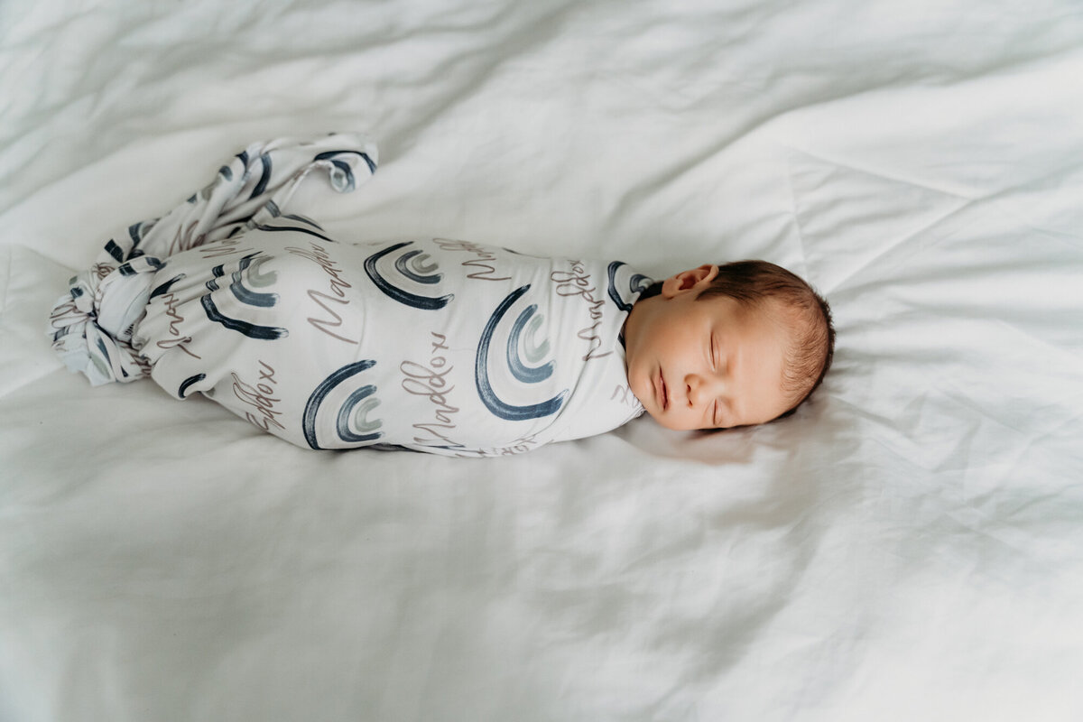 Newborn Photography, Baby boy laying on his back sleeping while he is swaddled.