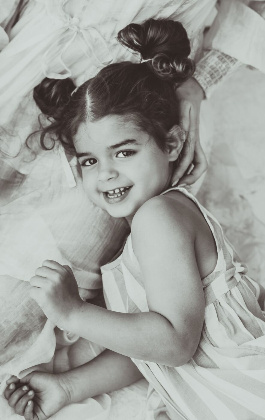 a pretty sweet girl laying down and her hair tied up in both sides and smiling