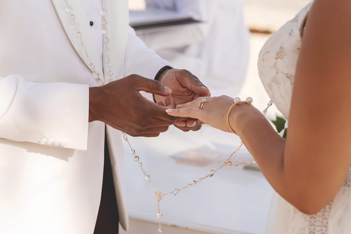 Groom putting on ring at wedding in Riviera Maya