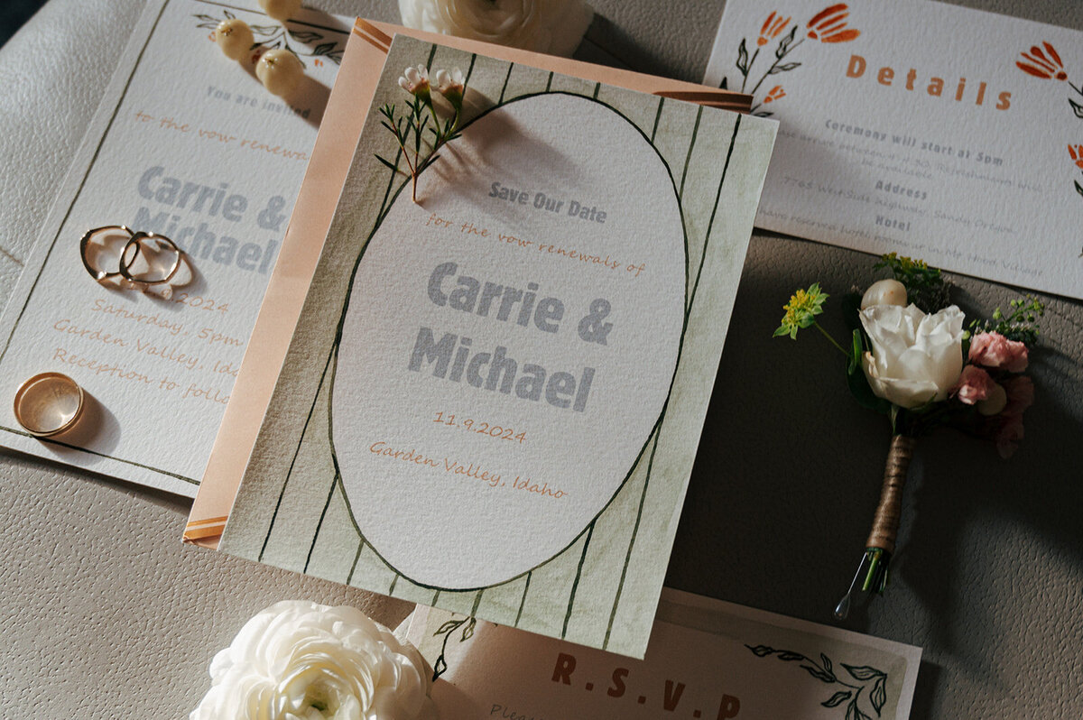 A flat lay of wedding details including invitations, rings and flowers.