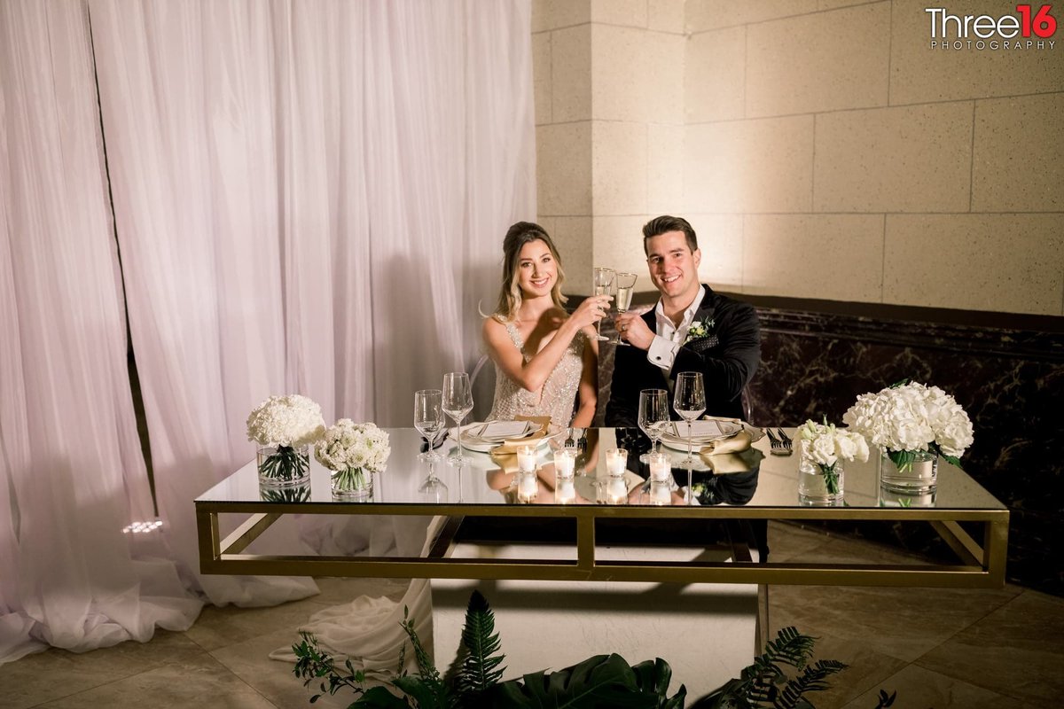 Bride and Groom toast each other sitting at the couples dinner table