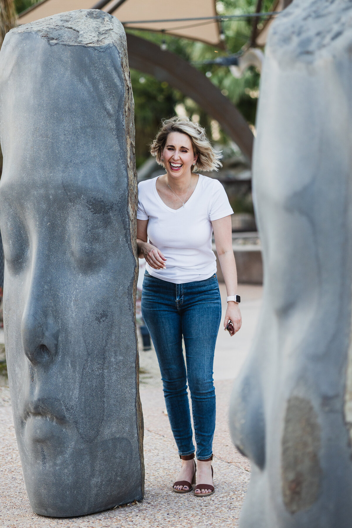 Sally Martinez laughing while standing next to large face sculpture art