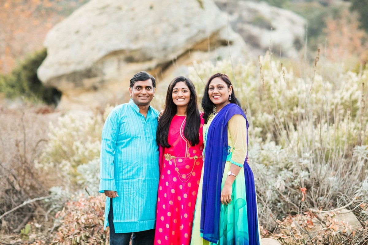 Mother and father pose for photos with their daughter during a nature hike wearing traditional Indian clothing