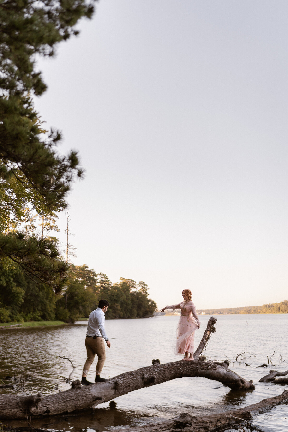 Offbeat wedding couple plays on a fallen tree branch on Lake Conroe after their intimate forest elopement
