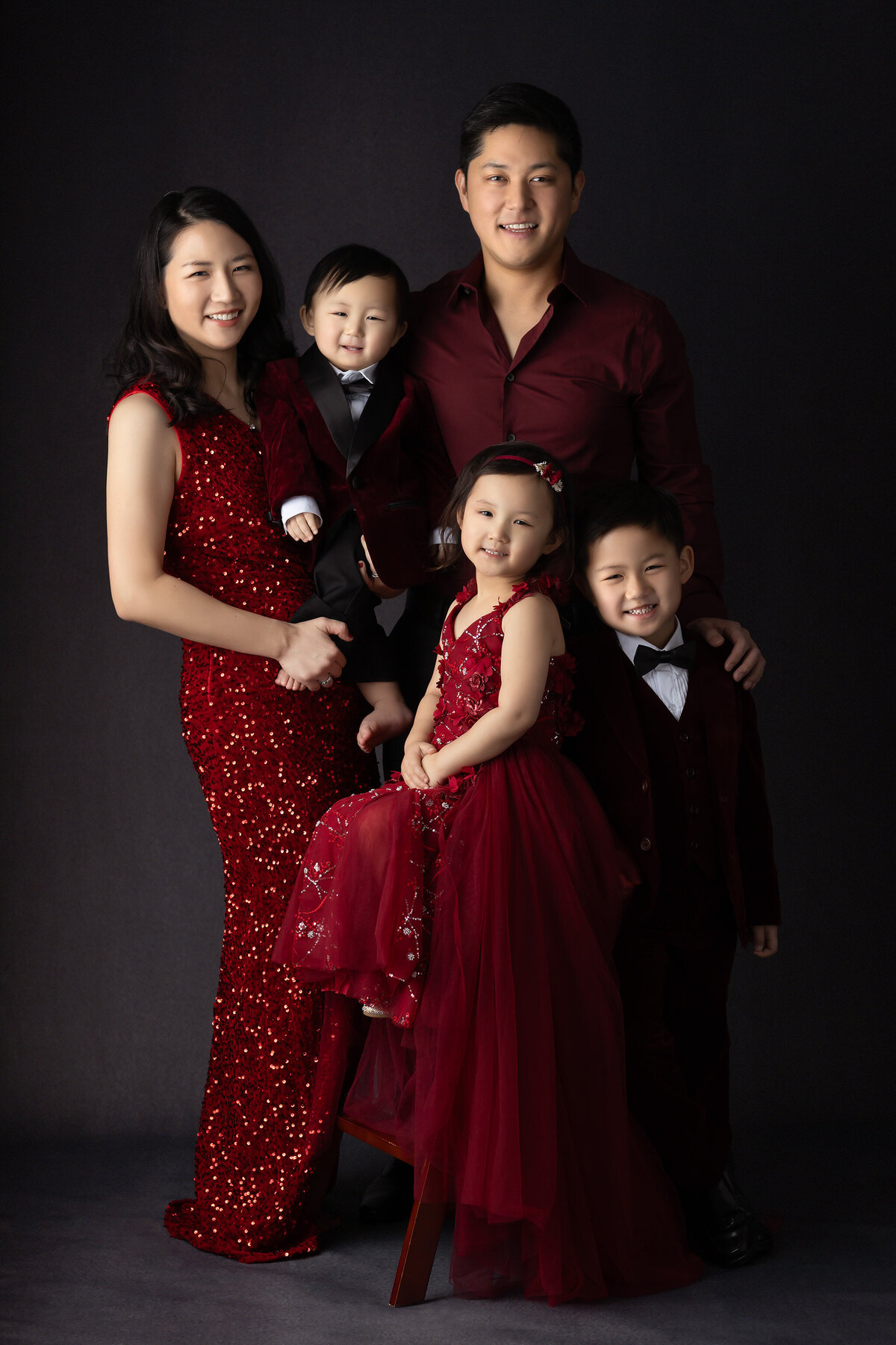 Dallas milestone photographer captures a stylish family portrait with matching red attire, showcasing elegance and warmth.