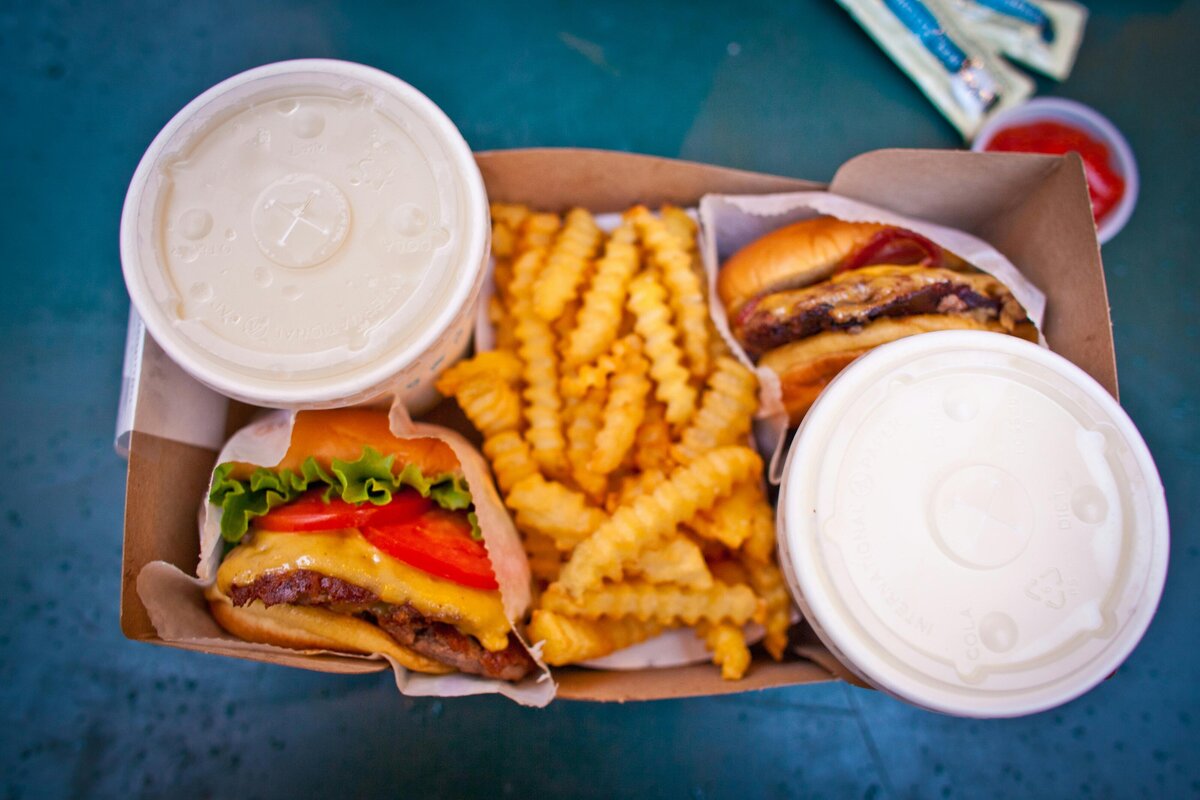 overhead shot of a box with hamburgers, french fries and drinks from a quick-service restaurant