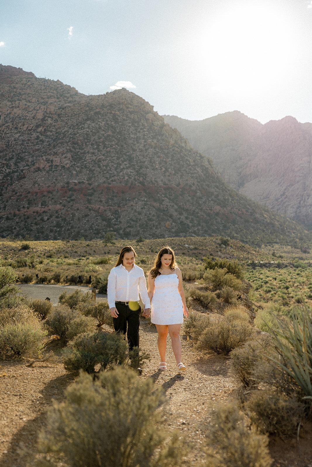 Engaged couple walking with mountains in the background in Nevada