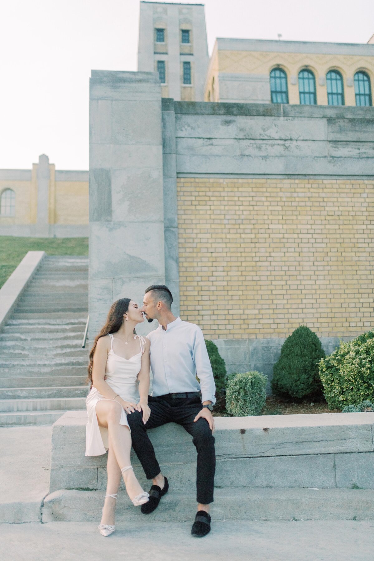 Couple sharing a joyful kiss, lost in a moment of pure love and happiness against the stone walls of Toronto’s RC  Harris Water Treatment Plant