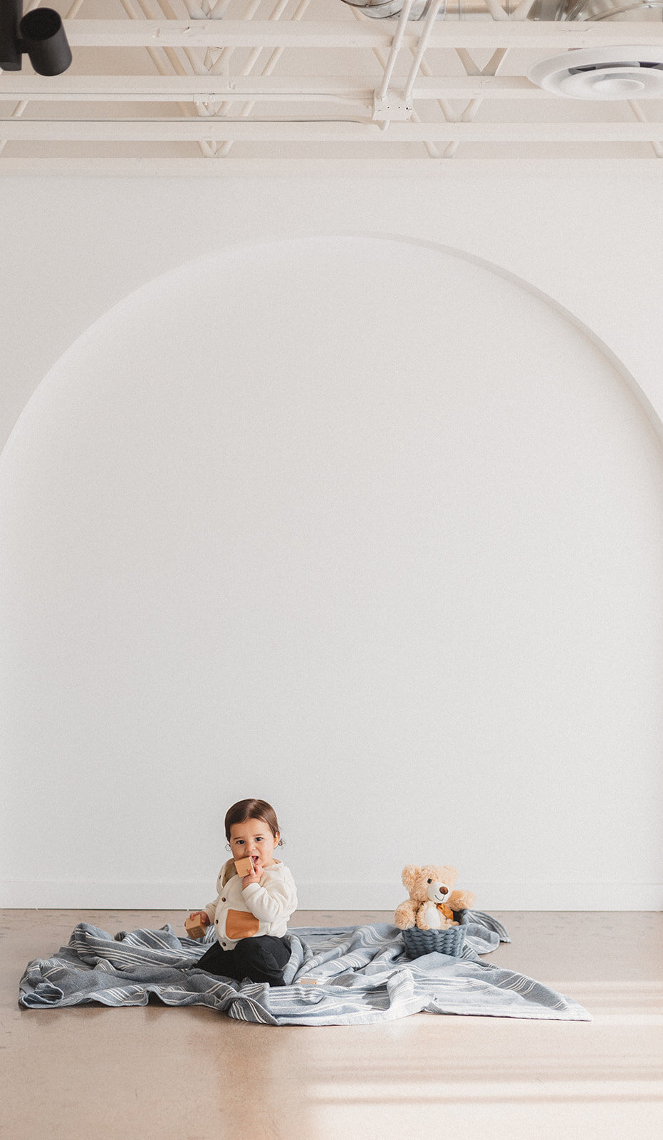 A little boy sits in front of a white wall.