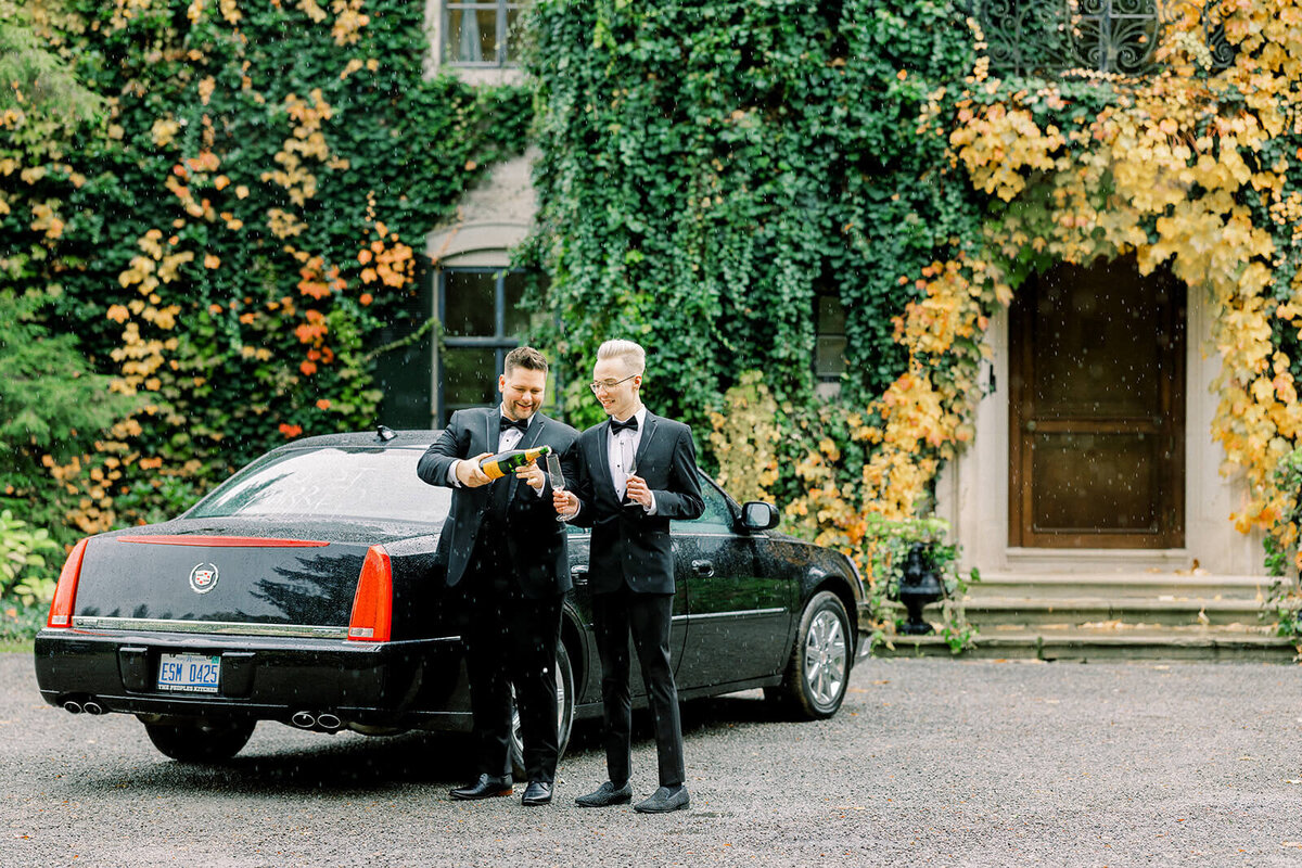 two grooms toasting champagne by just married car at Creencrest Manor front entrance