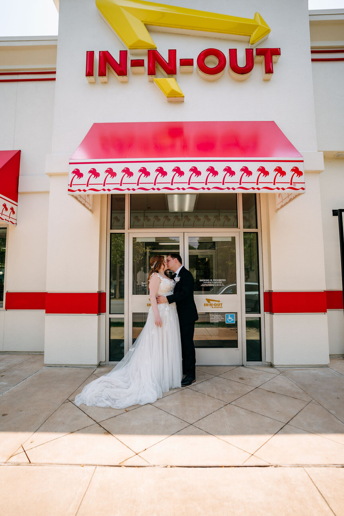 Bride and groom kissing outside an In-N-Out restaurant.