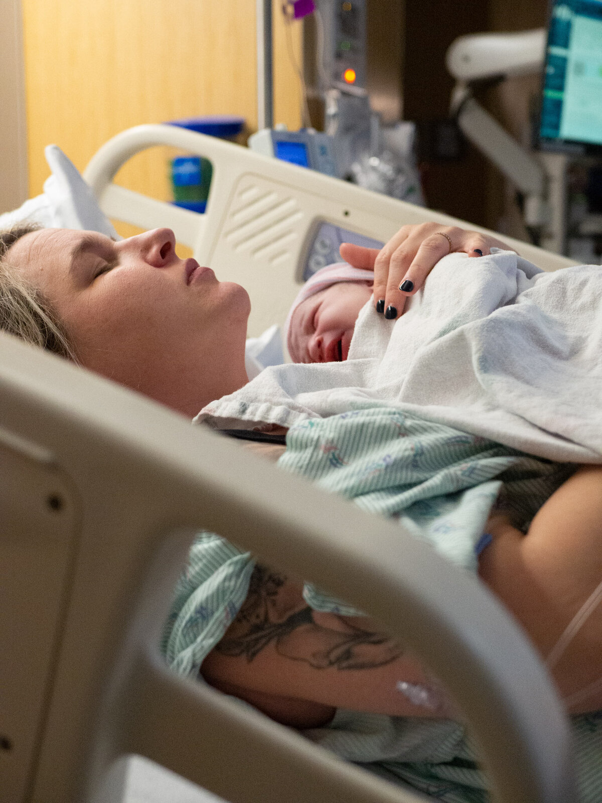 mother who has just given birth at Overlake Childbirth Center in Bellevue, WA is holding her baby for the first time with a calm look on her face  and her eyes are closed