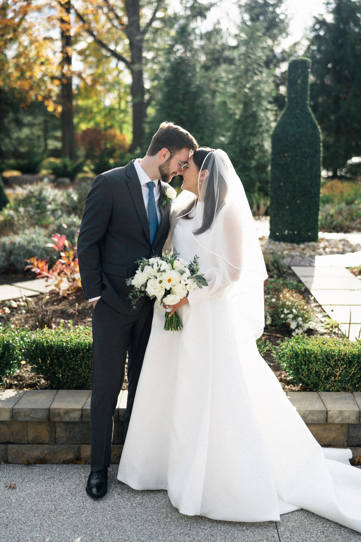 Bride and groom touching foreheads, holding bouquet during fall wedding in Cleveland