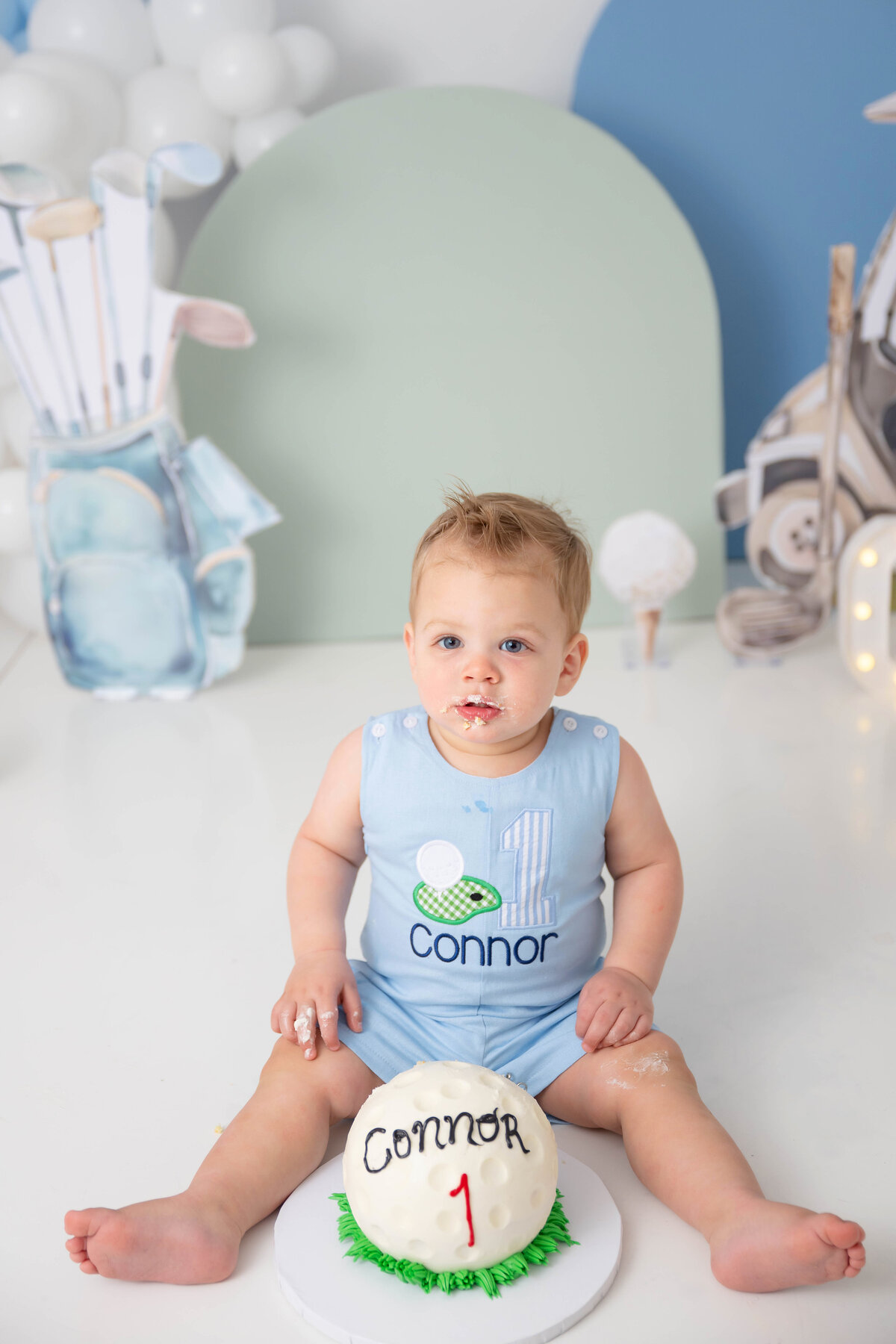 With white frosting on his lips, baby sits with a blank stare in his eyes. 