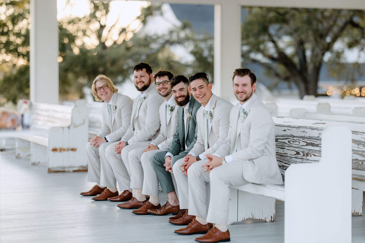 groom and groomsmen sitting on bench inside of wedding chapel