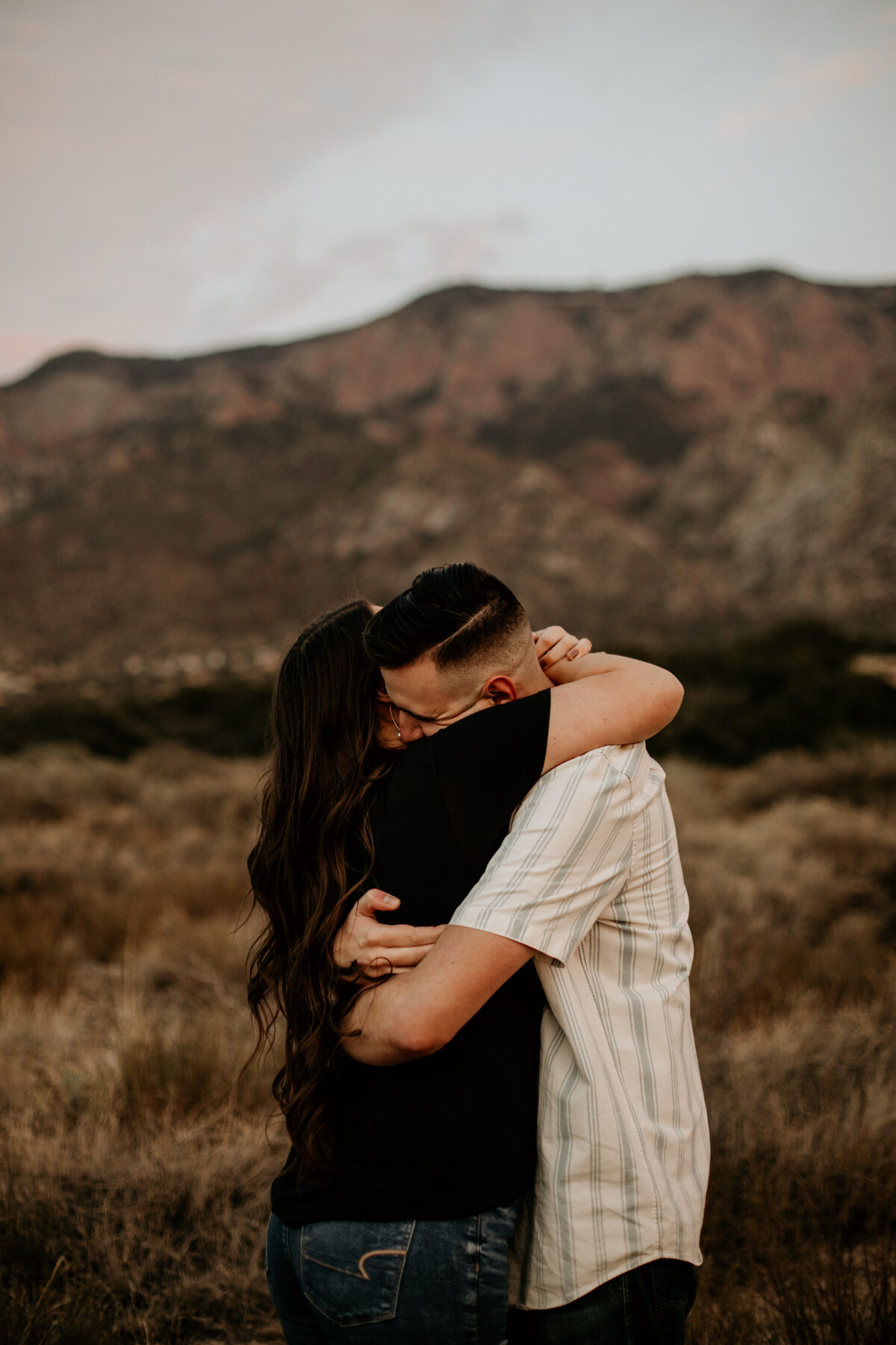 engaged couple hugging tight in front of a mountain