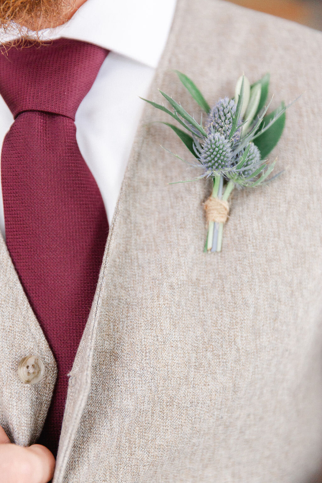 Dusty blue boutonniere, wine colored tie.