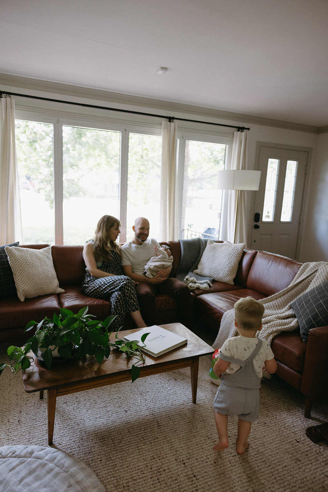 Family candidly plays in living room of their mid-century modern home for documentary style family photos. 