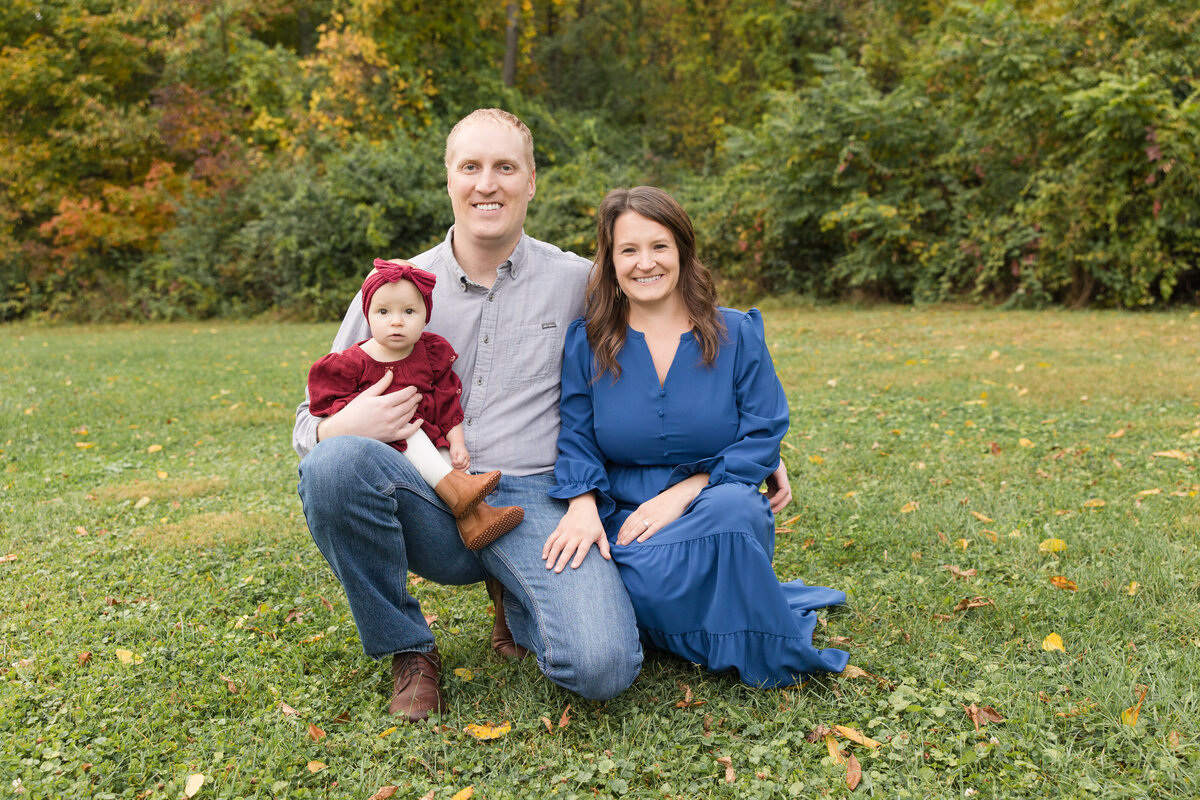 A family crouching on the grass smiling at the camera