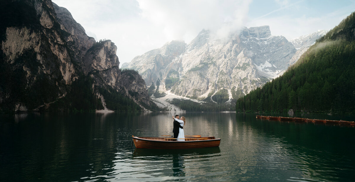 Dolomites Elopement with bride and groom standing in a rowboat on Lago di Braies with mountains in the back