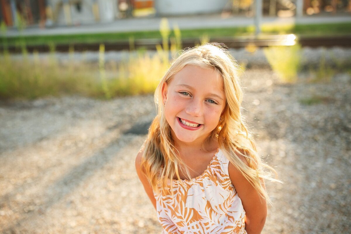  blonde-girl-smiling-in-warm-golden-light-during-an-outdoor-child-portrait-session-in-the-bargersville-area-of-indianapolis-which-is-on-the-southside-of-indianapolis-on-main-street