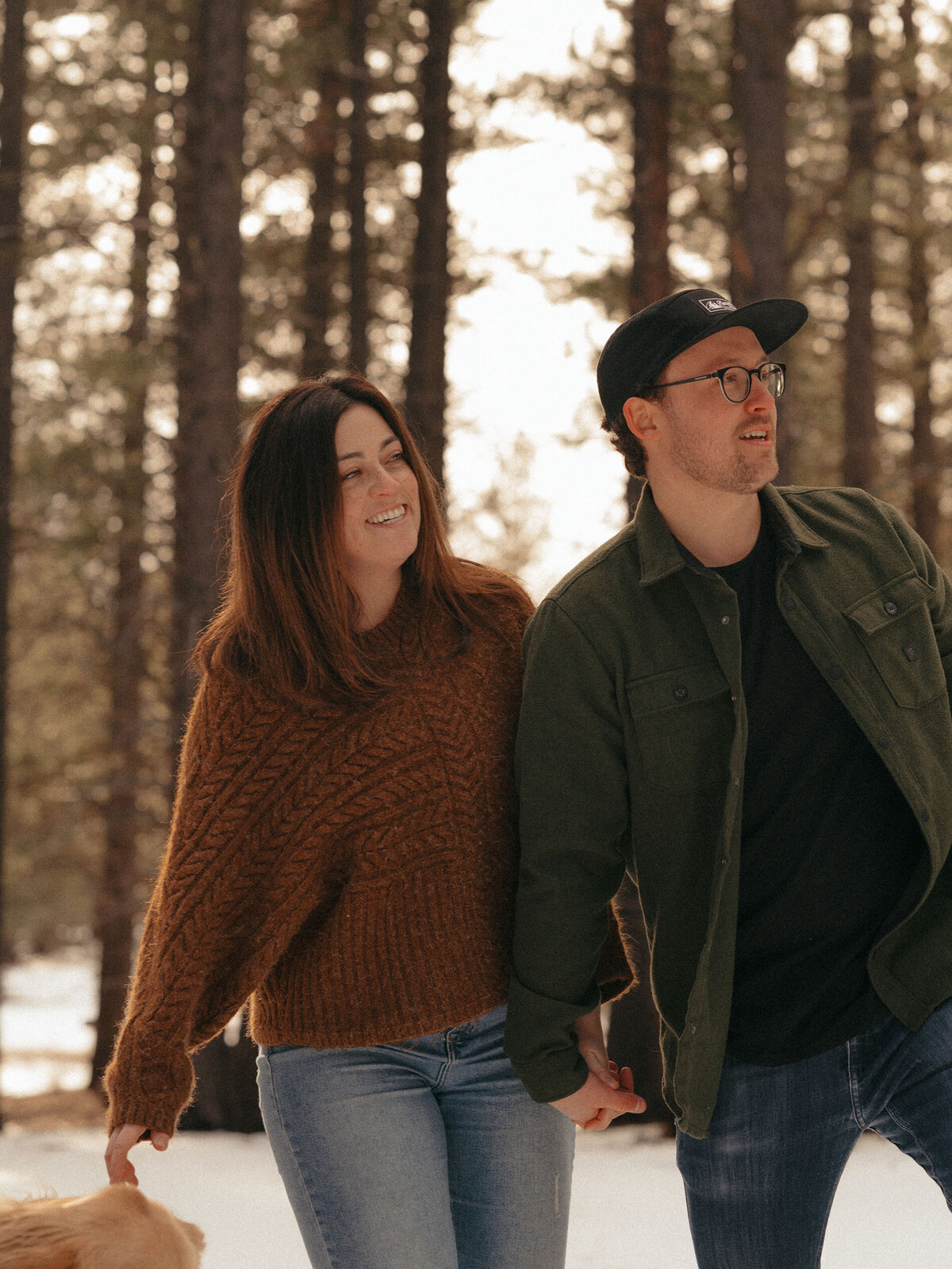 engaged couple walking through the trees in the snowy outdoors in Bend, Oregon