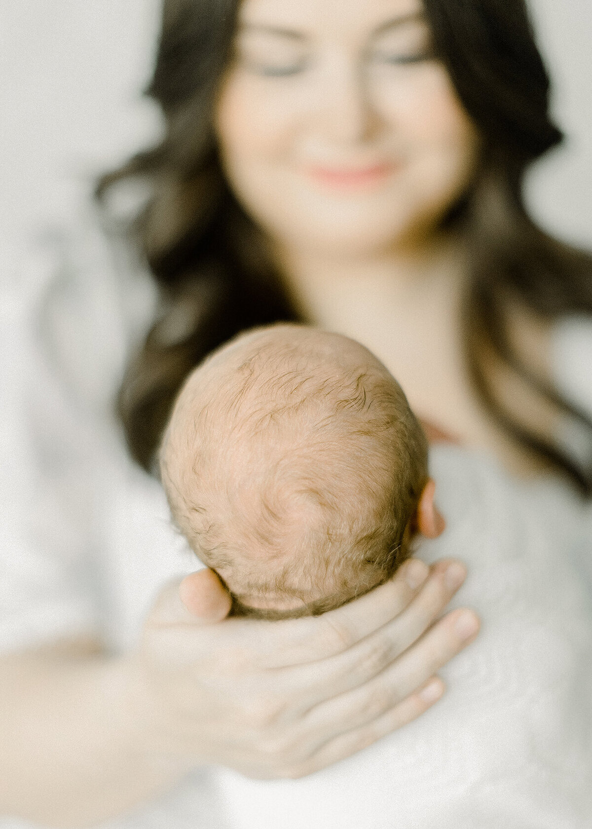 Close up detail shot of a newborn babies head as his mother holds him.