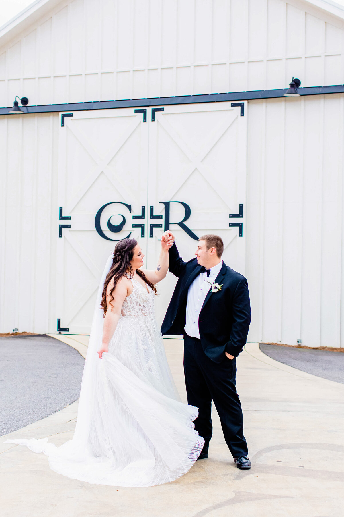bride and groom dancing in front of barn