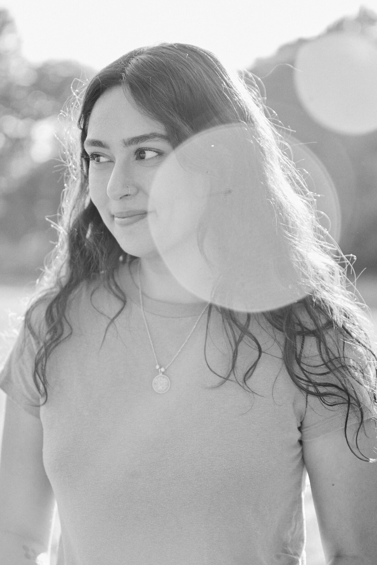A woman smiles, looking away; black & white photo.  Shortly after she was proposed to in a park in Queens, New York City
