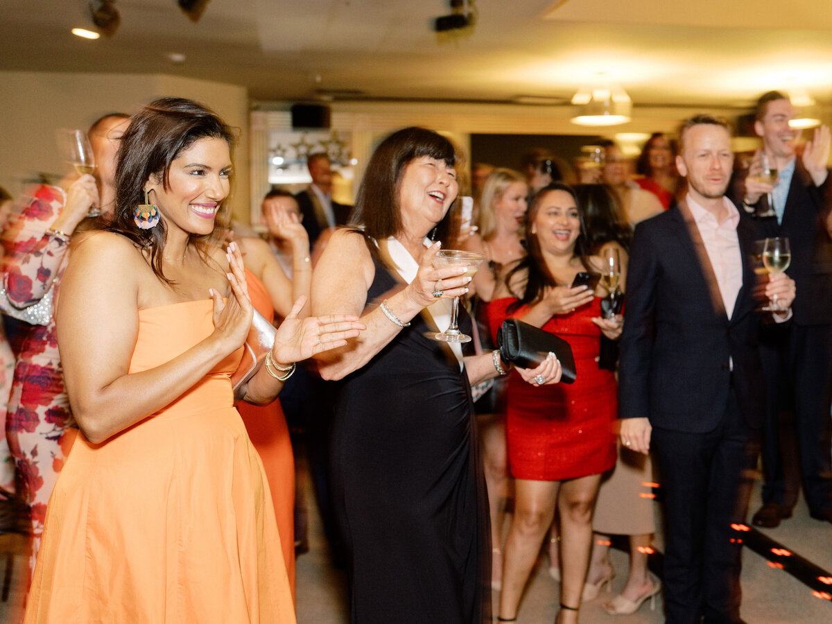 Guests enjoying themselves at a vibrant event, clapping, smiling, and socializing, highlighting the joyful and festive spirit of the reception.