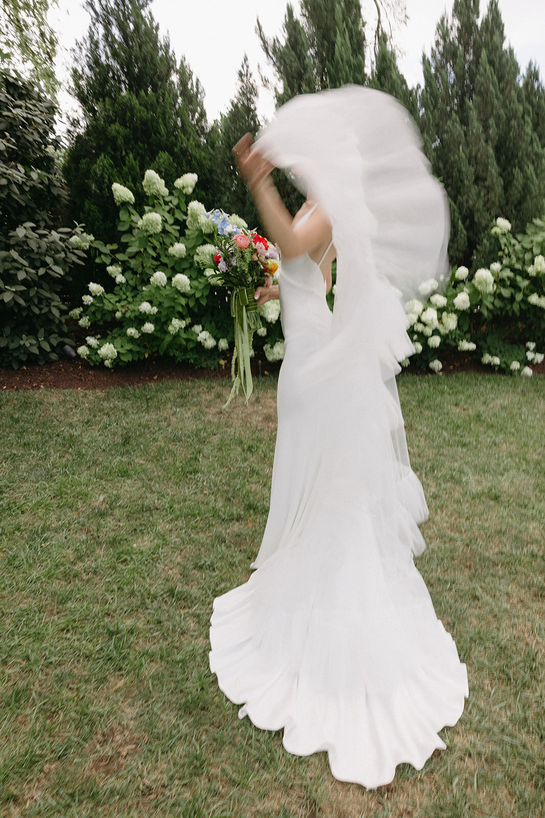 Bride’s cathedral-length veil flowing in the wind while she straightens out her dress.