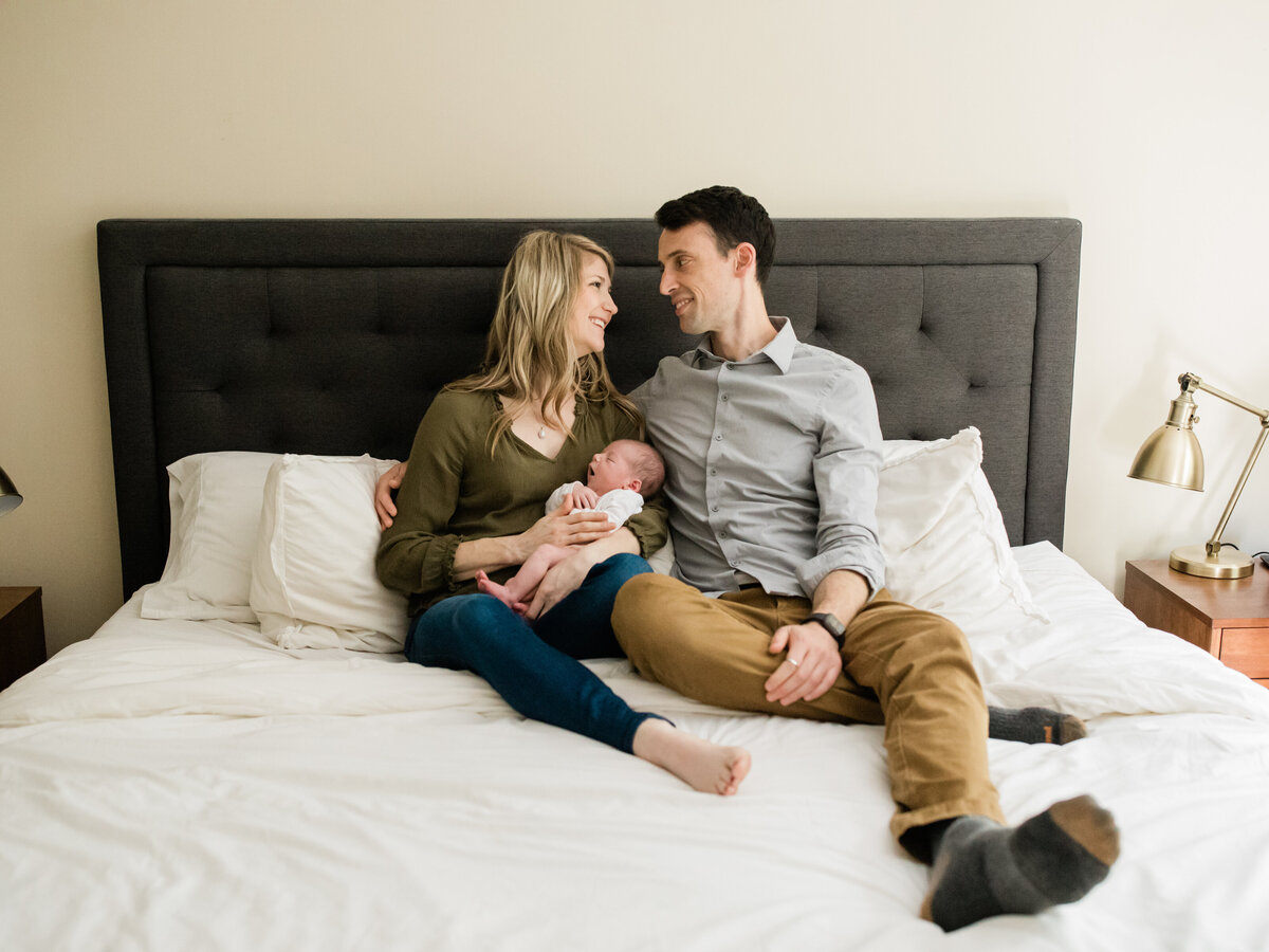 family sitting on bed for newborn in home lifestyle photography session cleveland newborn photographer