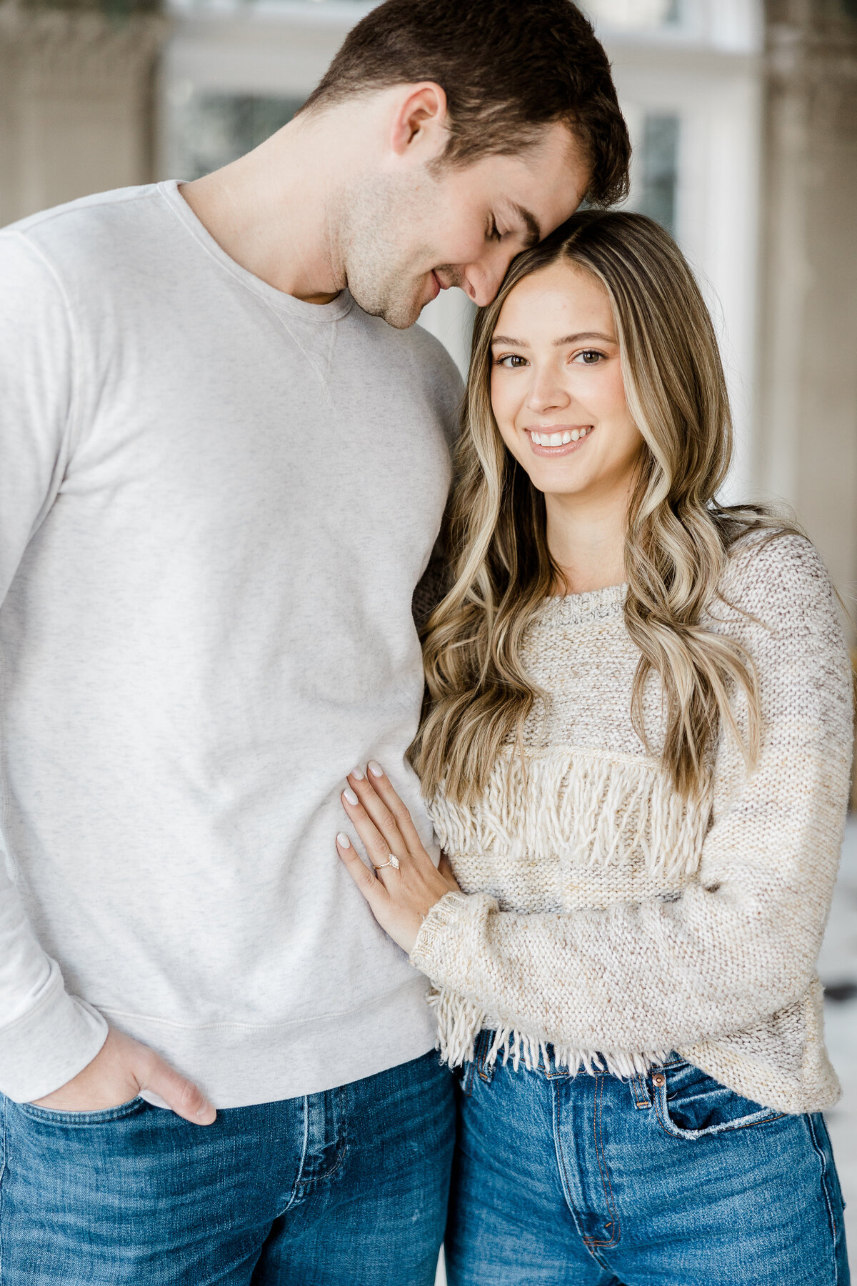 girl smiling at camera while fiance snuggles her